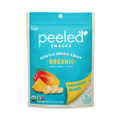 Product packaging showing a vibrant turquoise blue Peeled Snacks Gently Dried Fruit Paradise Blend pouch featuring a ripe mango, a golden pineapple slice, and three white banana rounds, clearly marked USDA Organic and "Nothing Added"